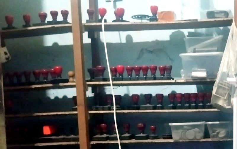 Rak kayu berisi banyak stempel bertangkai merah di toko Ahli Kunci Kraksaan Pajarakan
